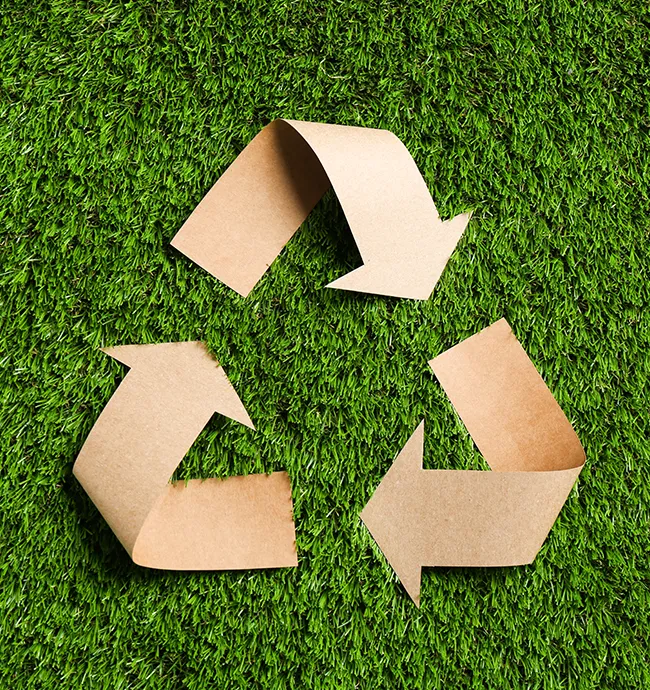 Recycling-Symbol aus Packpapier auf einer Wiese