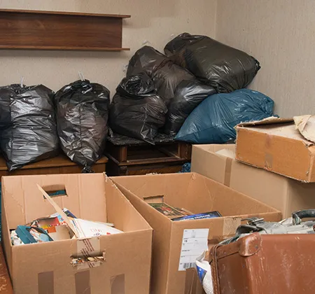 Müllsäcke und Kartons liegen auf alten Möbeln in einer Messiwohnung