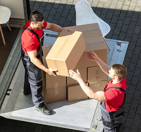 Zwei Umzugsprofis verladen Umzugskartons auf einen Lkw